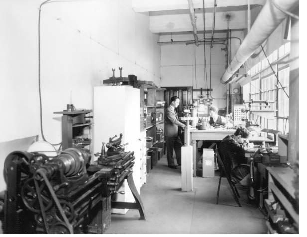 A historic black-and-white photograph of the Drew Company print shop, with staff working at the benches.