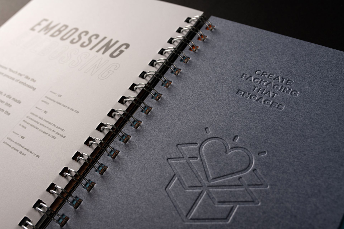 A Nice Package book spread on embossing — type and a mark raised off a dark page with no ink.