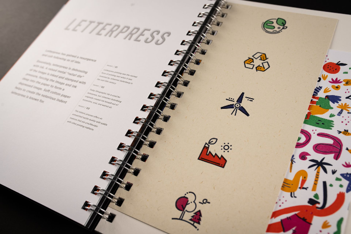 An open specimen book turned to its letterpress spread, marks pressed into soft cream stock.