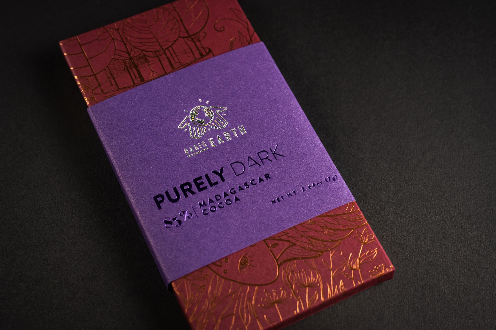 The Basic Earth confection carton — copper and holographic foil over debossed type.