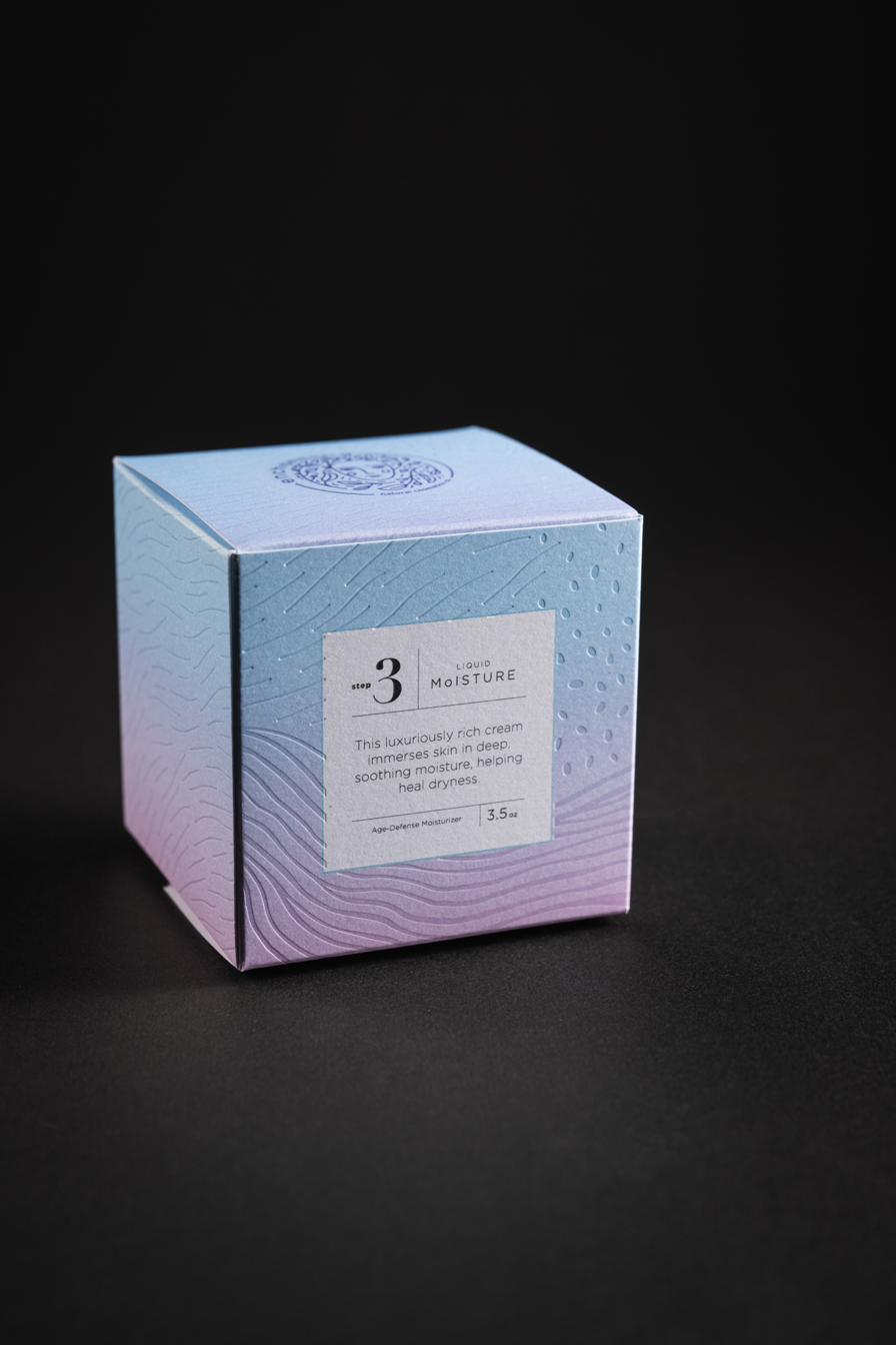 A cosmetics carton finished with engraving, emboss, and holographic foil on a gradient stock.