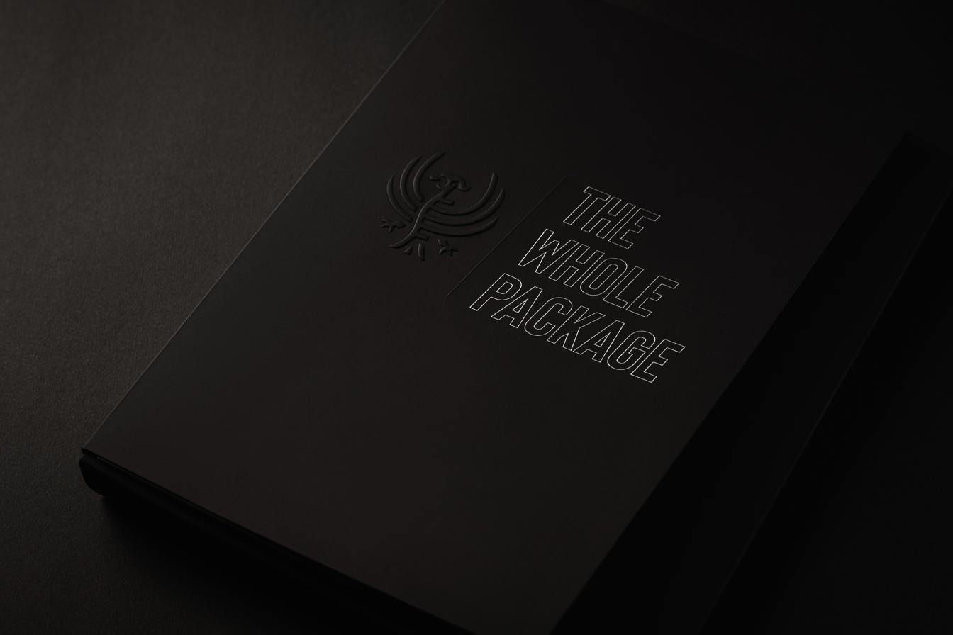 A closed slipcase on matte black board with a blind-embossed seal.